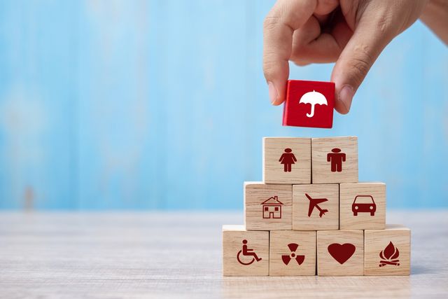 Cubes en bois illustrant les domaines assurés : santé, habitation, automobile, voyage et famille